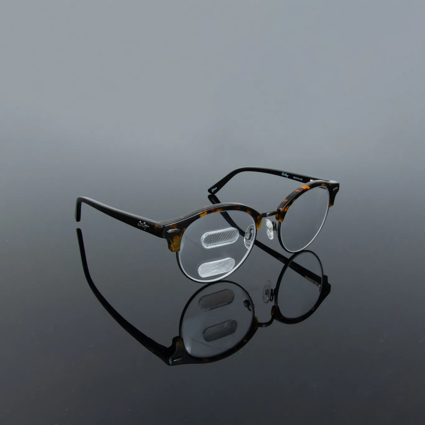 Round, tortoise-shell eyeglasses with specialized lenses designed for visual comfort, displayed on a reflective surface.