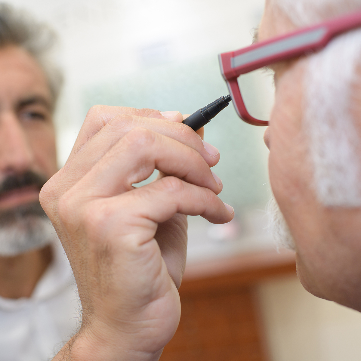 optician using and ophthalmoscope to look into a patients eyes