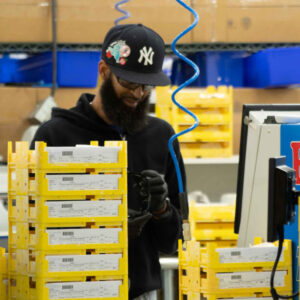 Chadwick Optical staff member works in the lab, surrounded by yellow trays of lenses, focusing on organizing or preparing lenses for processing.