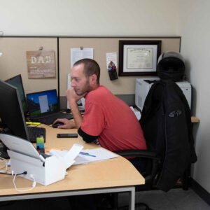 An employee focusing on tasks at a dual-monitor setup in an office cubicle at Chadwick Optical.