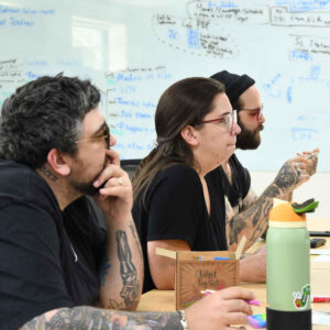 Chadwick Optical team members, attentively listening in a meeting, with a whiteboard full of notes in the background.