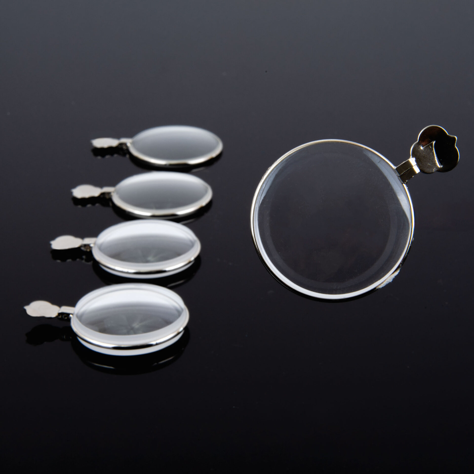 Close-up of five round lenses with metal frames on a black background.
