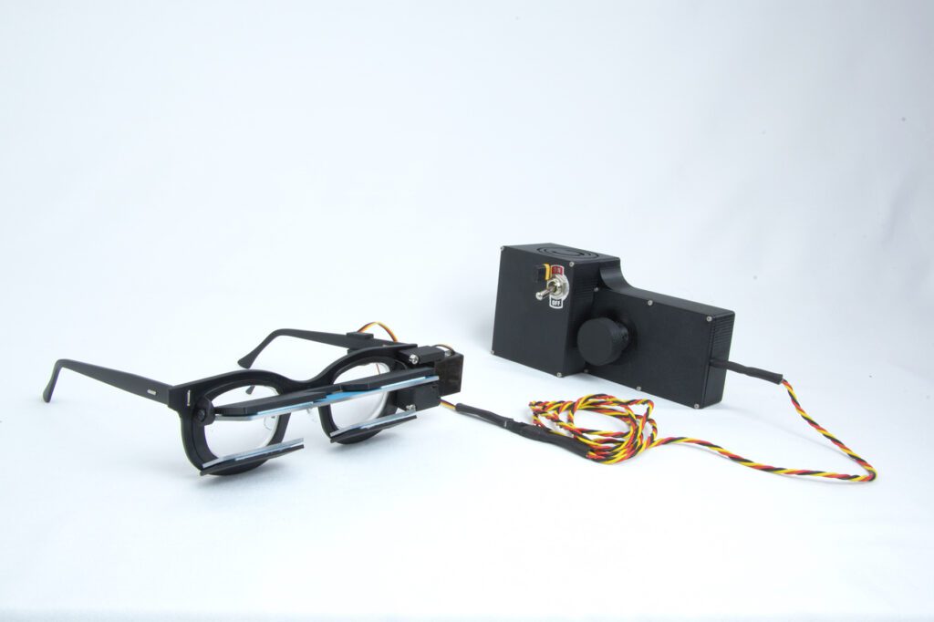 PrPeriscoping glasses setup connected to a control box with wires, developed by Chadwick Optical.totype glasses connected to a black control box with wires and an on/off switch, used for engineering or optical testing at Chadwick Optical.