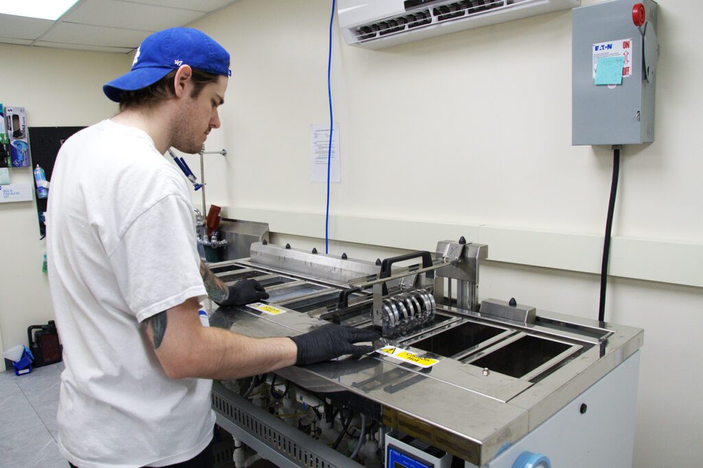 Man in a blue cap and gloves operates an ultrasonic cleaner at Chadwick Optical.