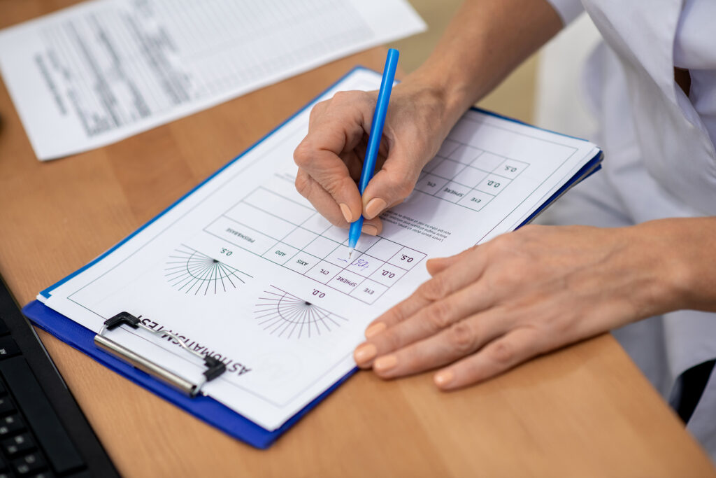 Doctor,Making,Notes.,Close,Up,Of,Eye,Doctor,Making,Notes Doctor making notes. Close up of eye doctor making notes while writing prescription for patient
