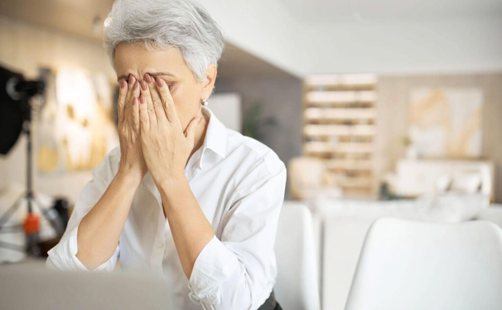 Woman holds head in hands, highlighting vision fatigue. Chadwick Optical's lenses ease strain, making comfort a reality.