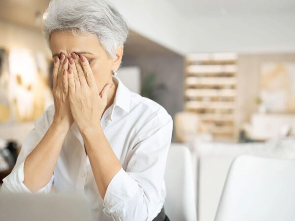 Woman holds head in hands, highlighting vision fatigue. Chadwick Optical's lenses ease strain, making comfort a reality.
