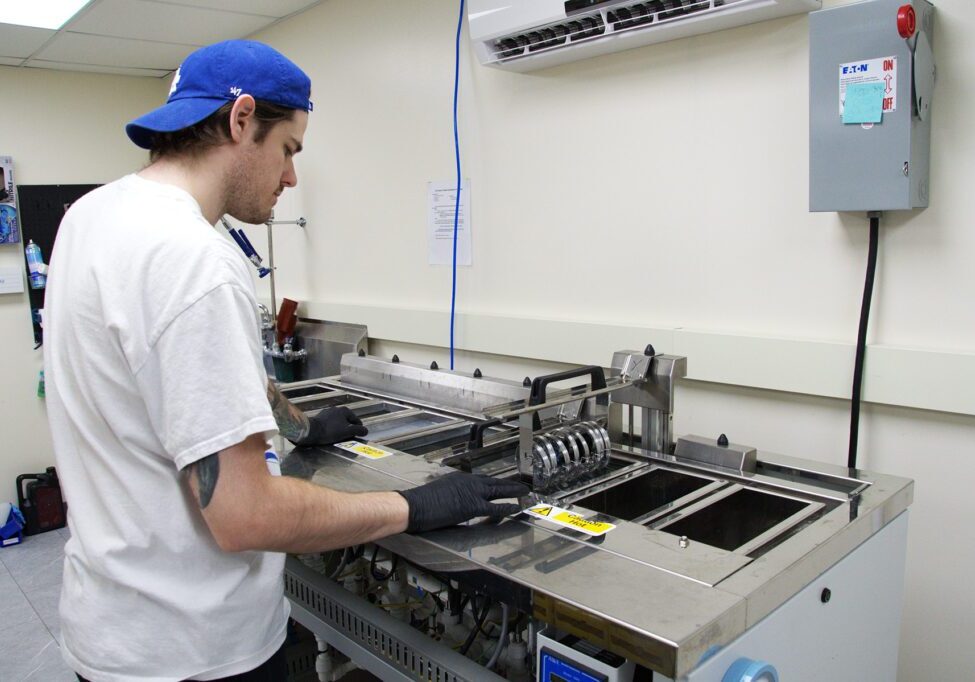 Man in a blue cap and gloves operates an ultrasonic cleaner at Chadwick Optical.